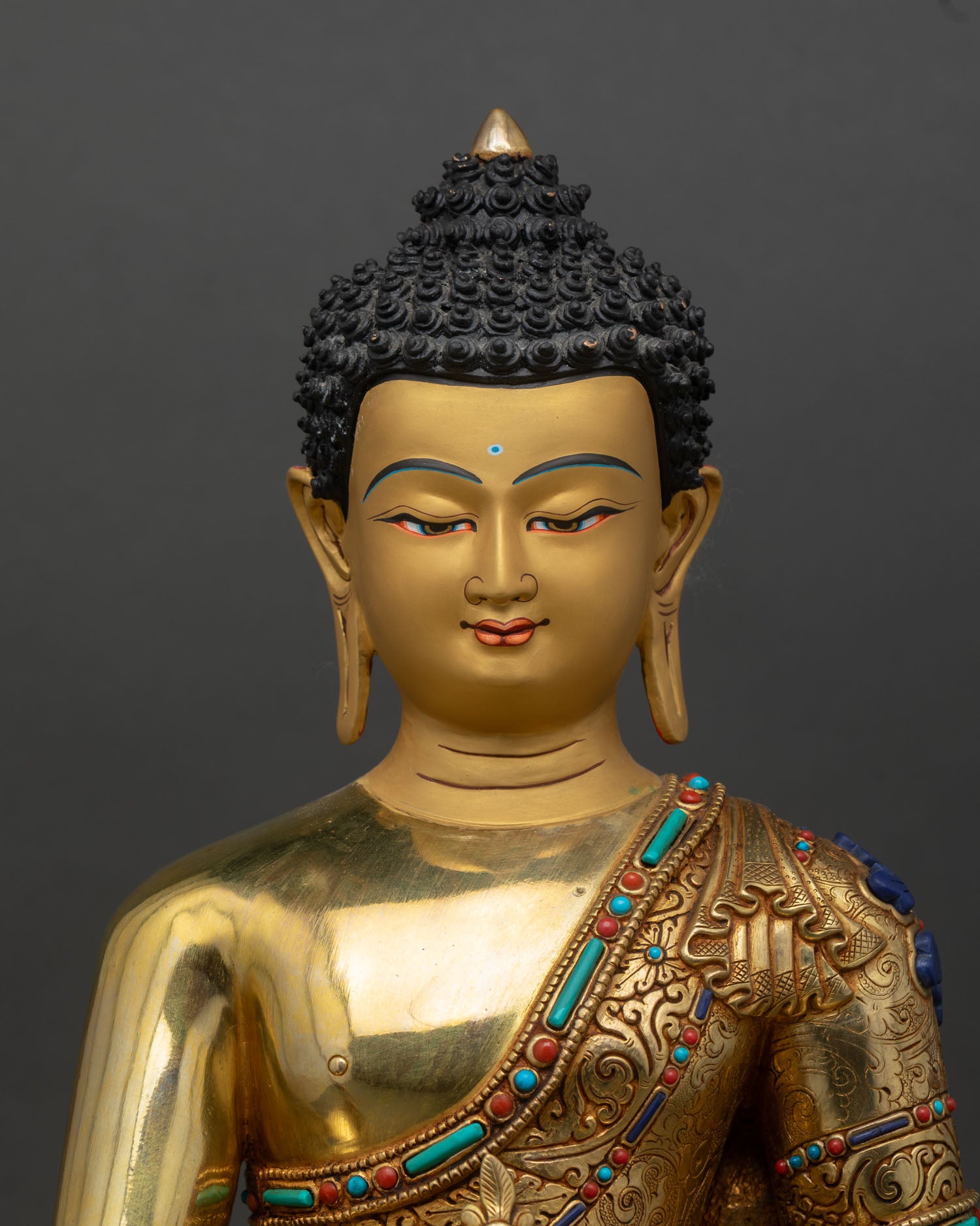 Medicine Buddha statue close up, handcrafted Tibetan Buddhist copper art with intricate gold fire gilded detailing