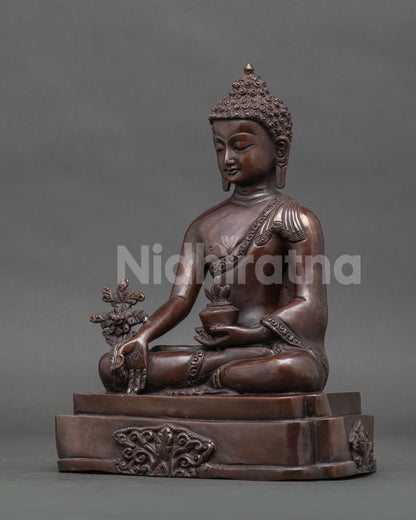 Medicine buddha statue seated on detailed pedestal oxidized copper.
