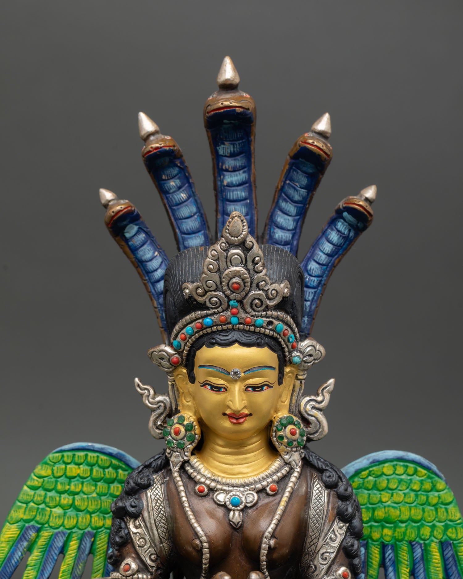 Naga Kanya close up half human face gold painted crown semi precious stones Himalayan sculpture