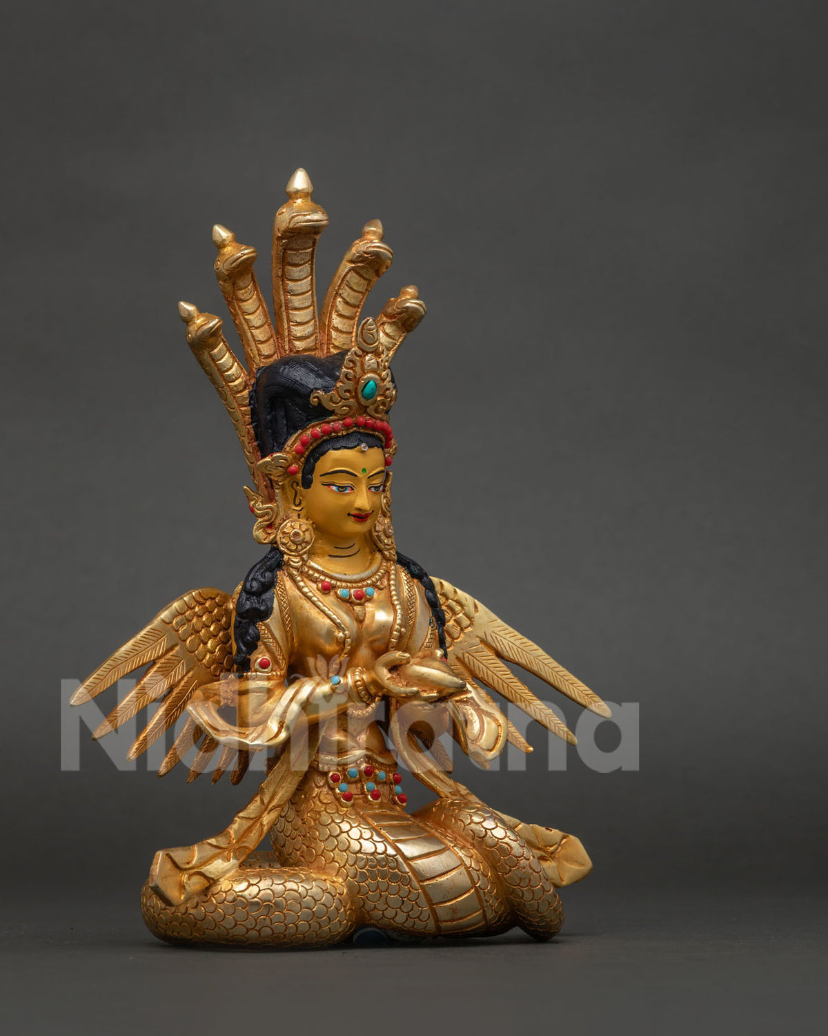 Naga Kanya serpent goddess statue holding a conch shell in graceful pose.