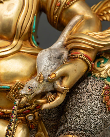 Namtoshe statue holding a silver jewel-spitting mongoose, symbol of wealth, beside filigree garment