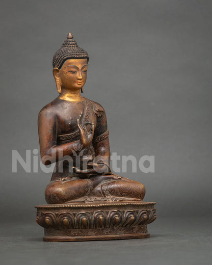 Nepalese Amoghasiddhi Buddha sculpture in oxidized copper holding sacred bowl in meditation pose.