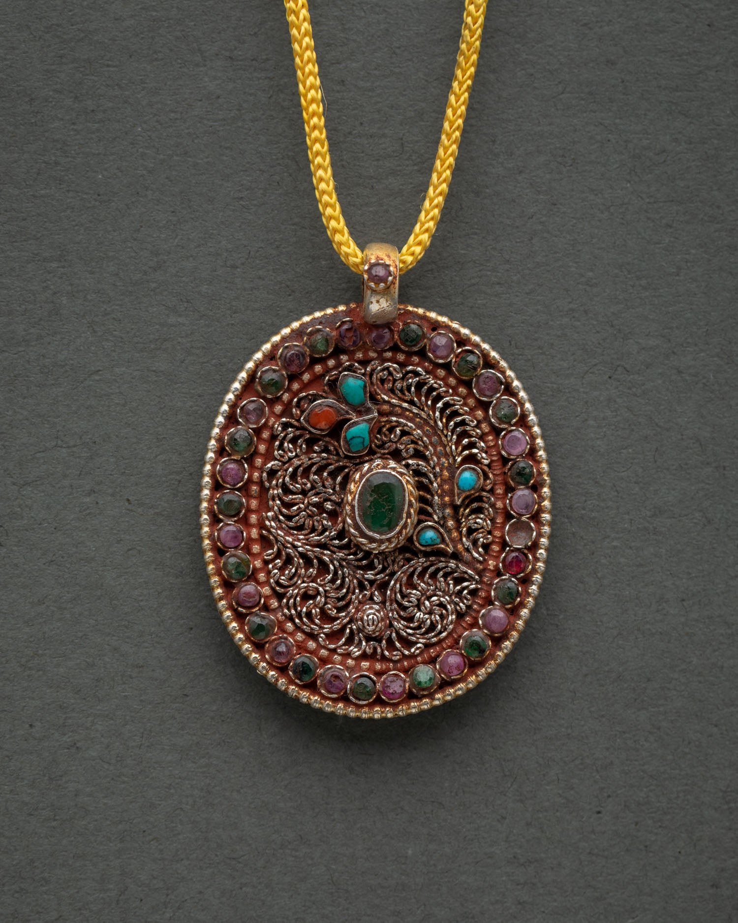 Nepalese Buddhist locket featuring intricate filigree artwork and semi precious stones