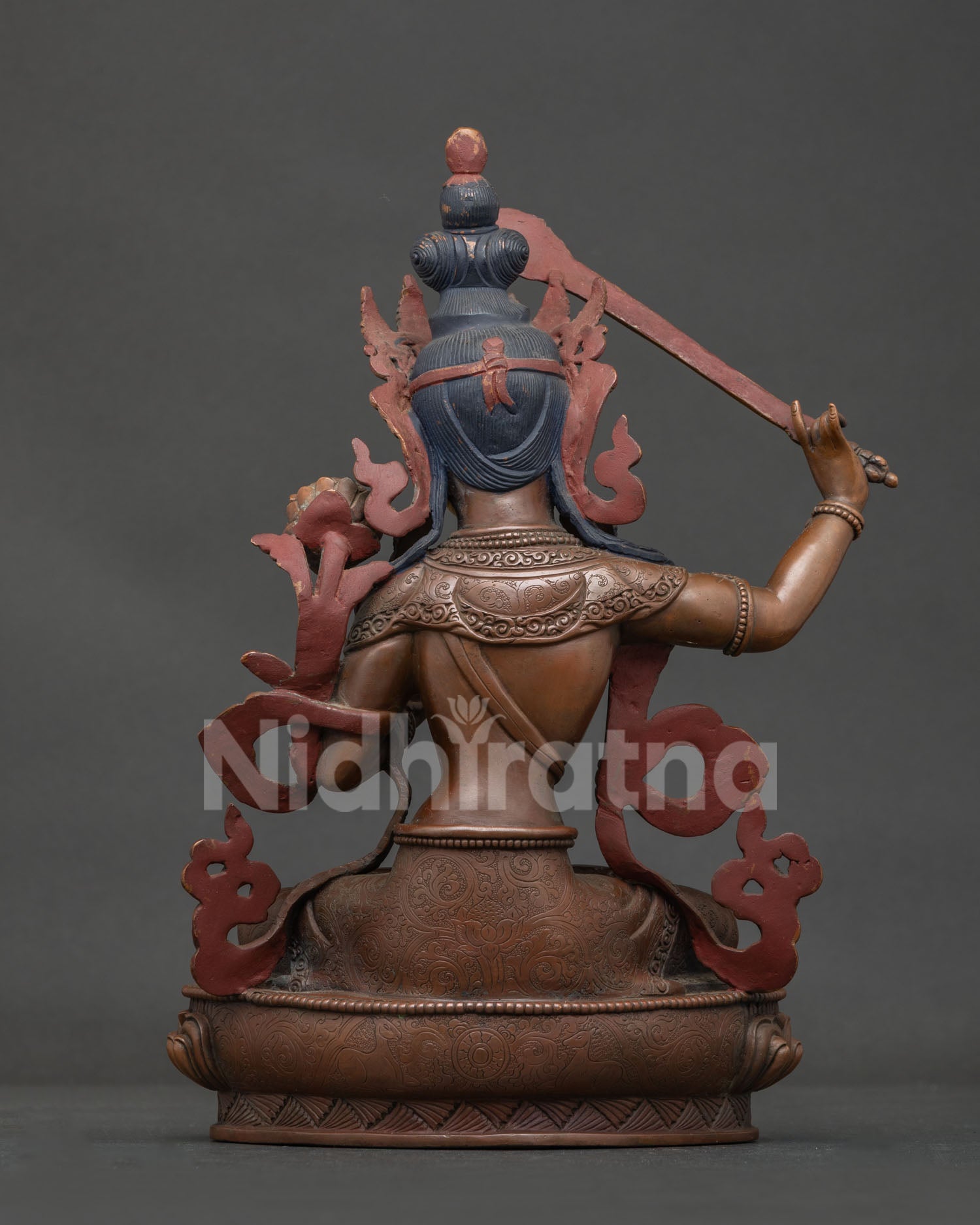 Nepalese manjushri statue with chemically oxidized copper finish and carved lotus pedestal.