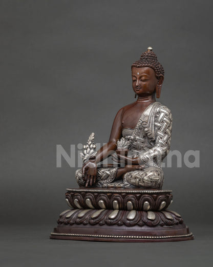 Medicine buddha bhaisajyaguru statue with serene expression and silver plated monk robe.