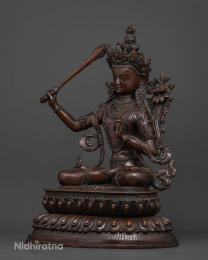 Oxidized copper Manjushri Buddhist statue holding the Prajnaparamita Sutra on a lotus flower, symbolizing transcendent wisdom.