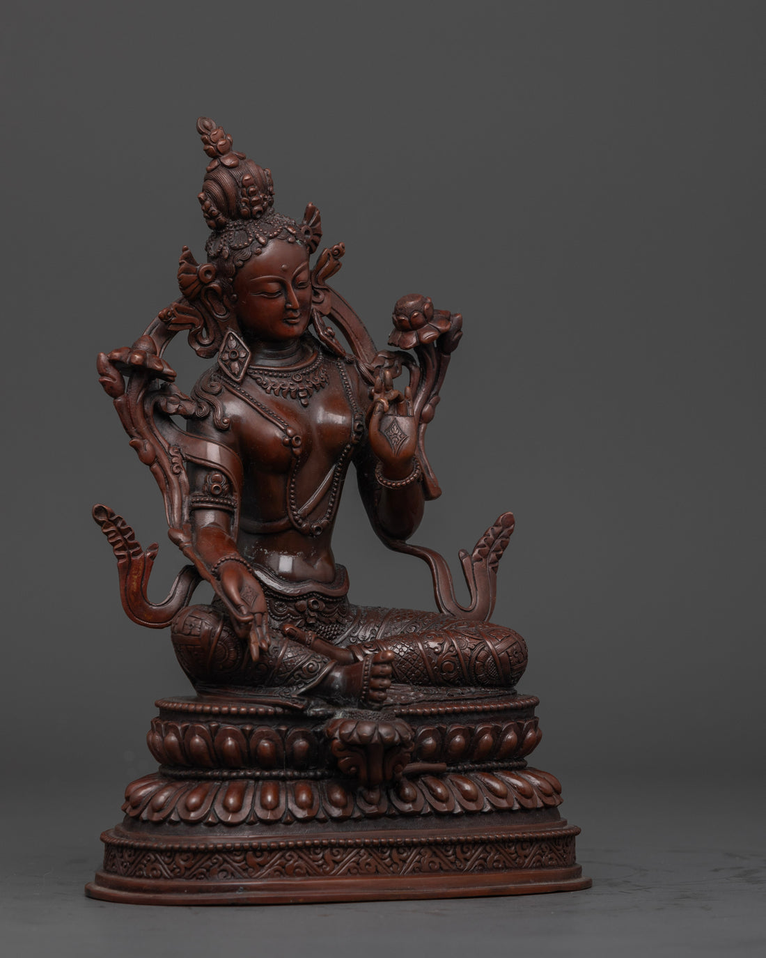 side view of intricately designed oxidized copper green tara statue