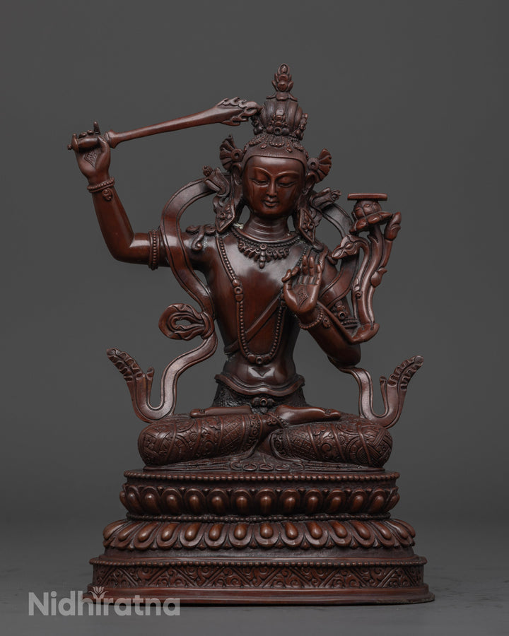 oxidized manjushri statue holding a sword with a book on a flower