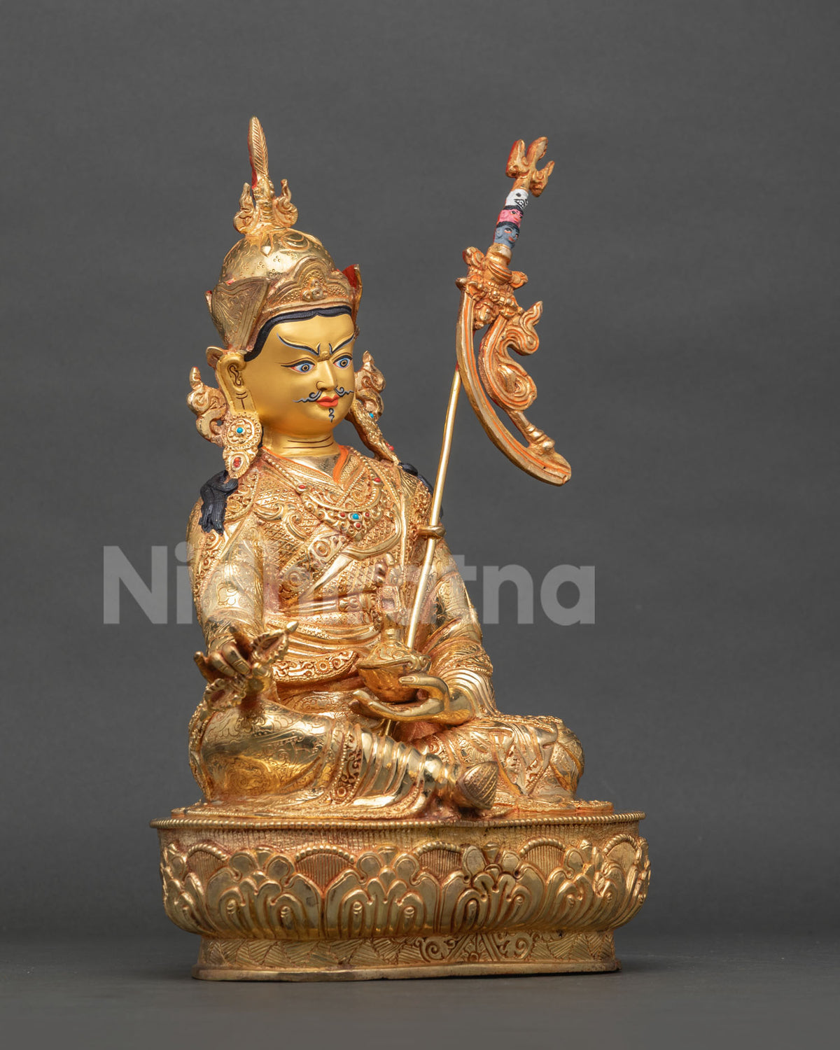 Padmasambhava Buddhist statue holding a vajra and skull cup with a traditional khatvanga staff