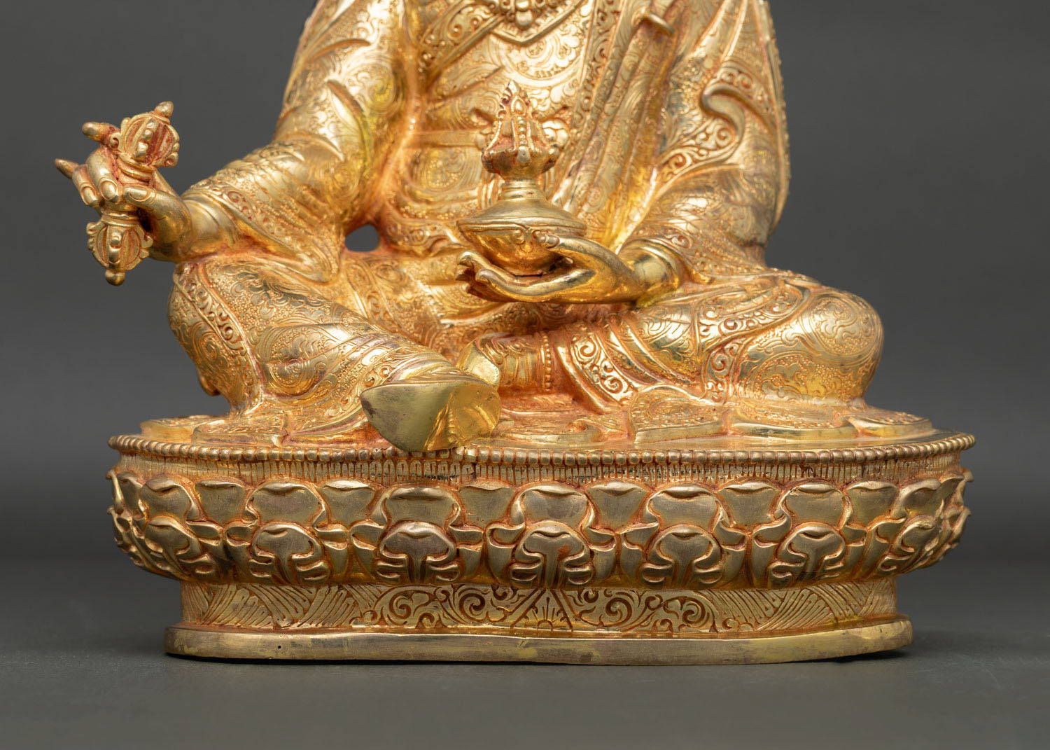 Padmasambhava statue seated on lotus throne with sacred Buddhist symbols and gold finish