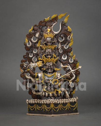 Rahula statue with three stacked heads, bow and arrow, skull base and flame halo in copper