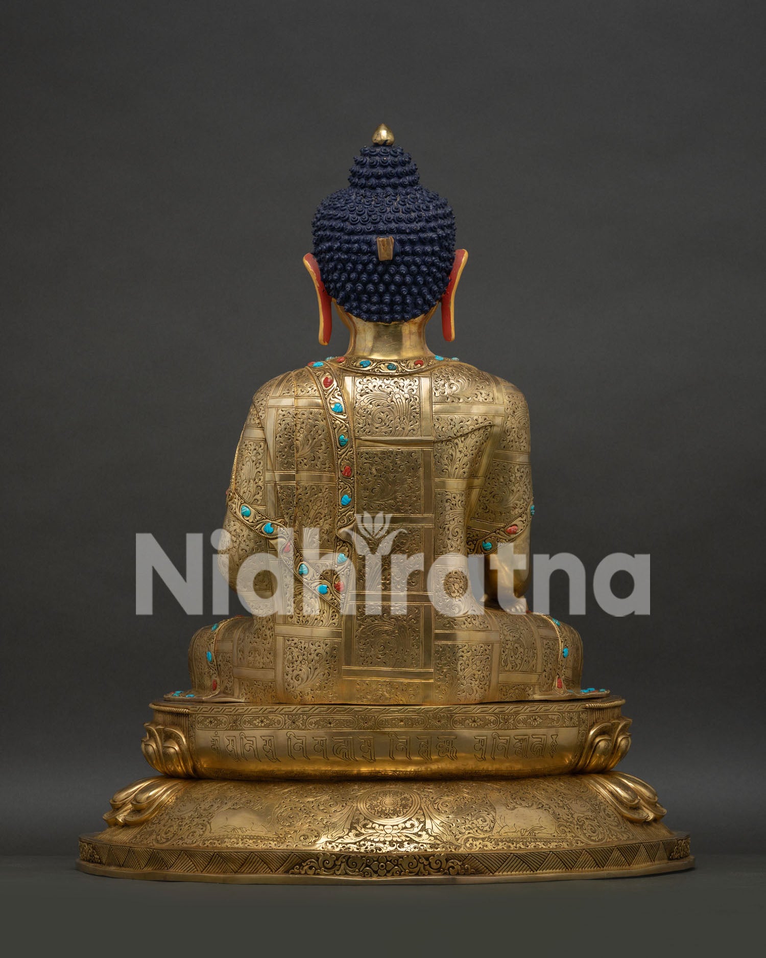 Rear view of gold-gilded Buddha statue showing engraved robe and hair knot