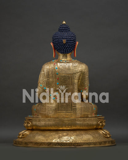 Rear view of gold-gilded Buddha statue showing engraved robe and hair knot