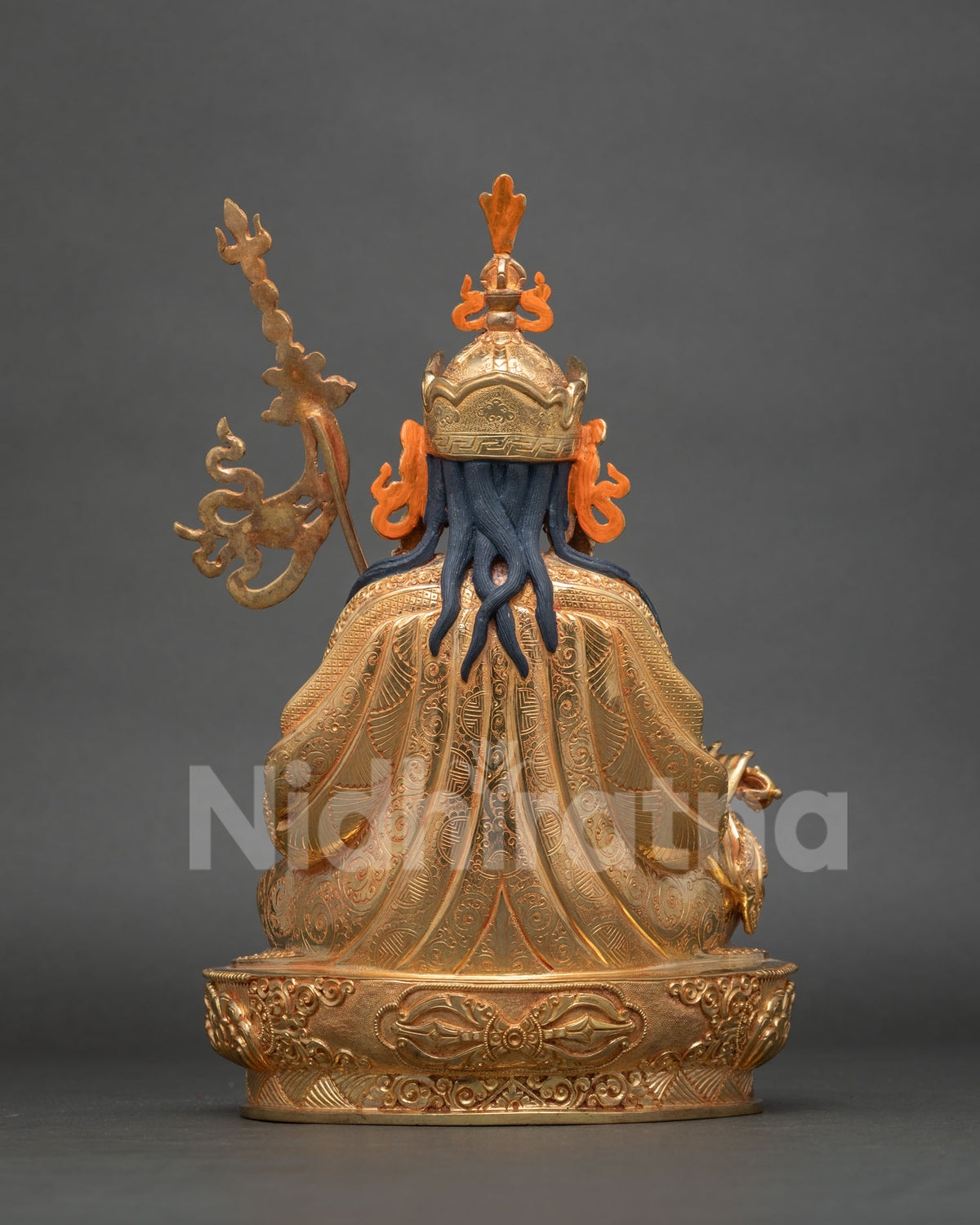Rear view of Guru Rinpoche statue with blue braids, orange hat ribbons, and lotus base