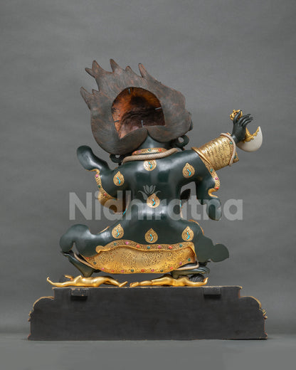 Rear view of Mahakala Bernagchen statue with raised kartika knife, black cloak and gold medallions