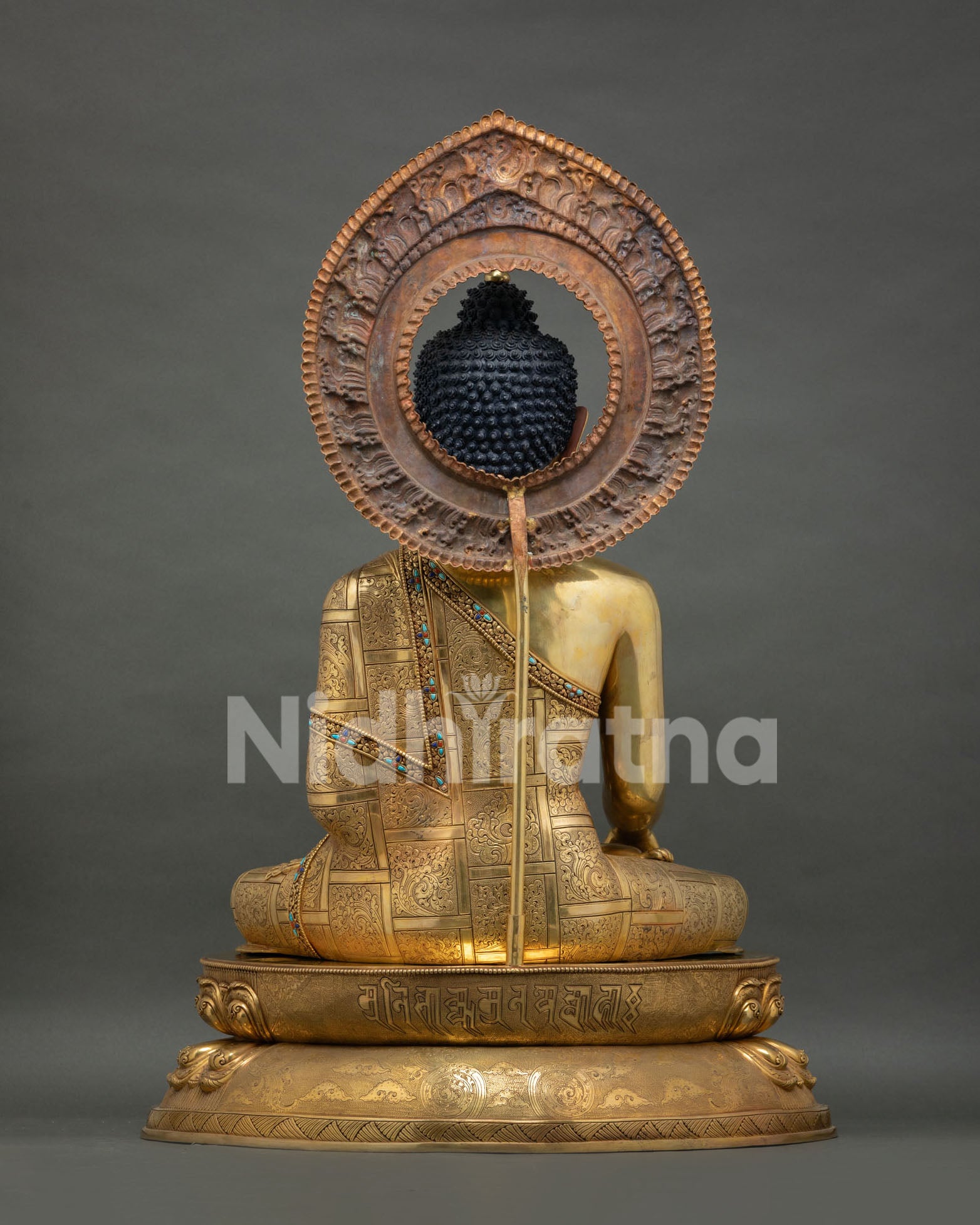rear view of shakyamuni buddha statue displaying detailed halo and robe engravings