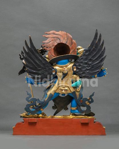 Rear view of Vajrakilaya statue showing garuda wings, gilded cloak and red painted base