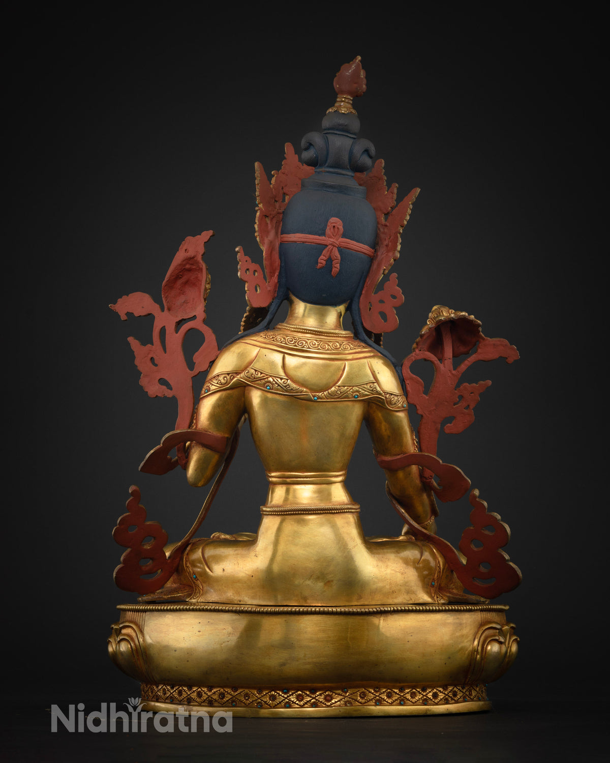 Rear view of White Tara Buddhist statue with red-painted back ornaments and gold lotus base
