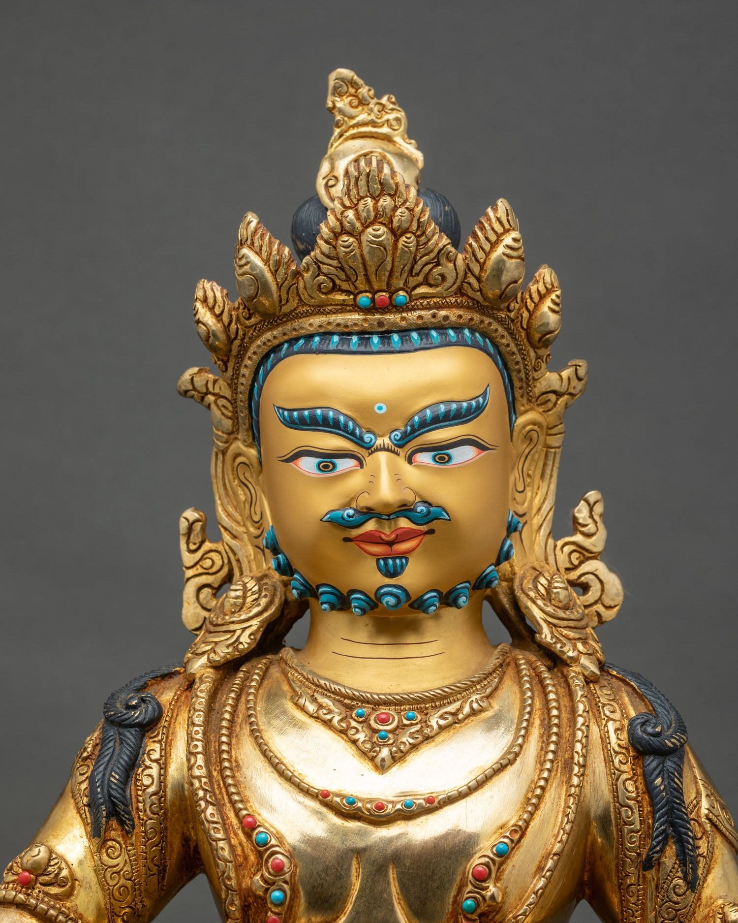 Regular close-up of Dzambhala statue showing intricate copper and gold details