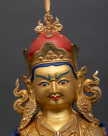 regular close-up of guru norlha statue showing gold-painted face and red lotus crown