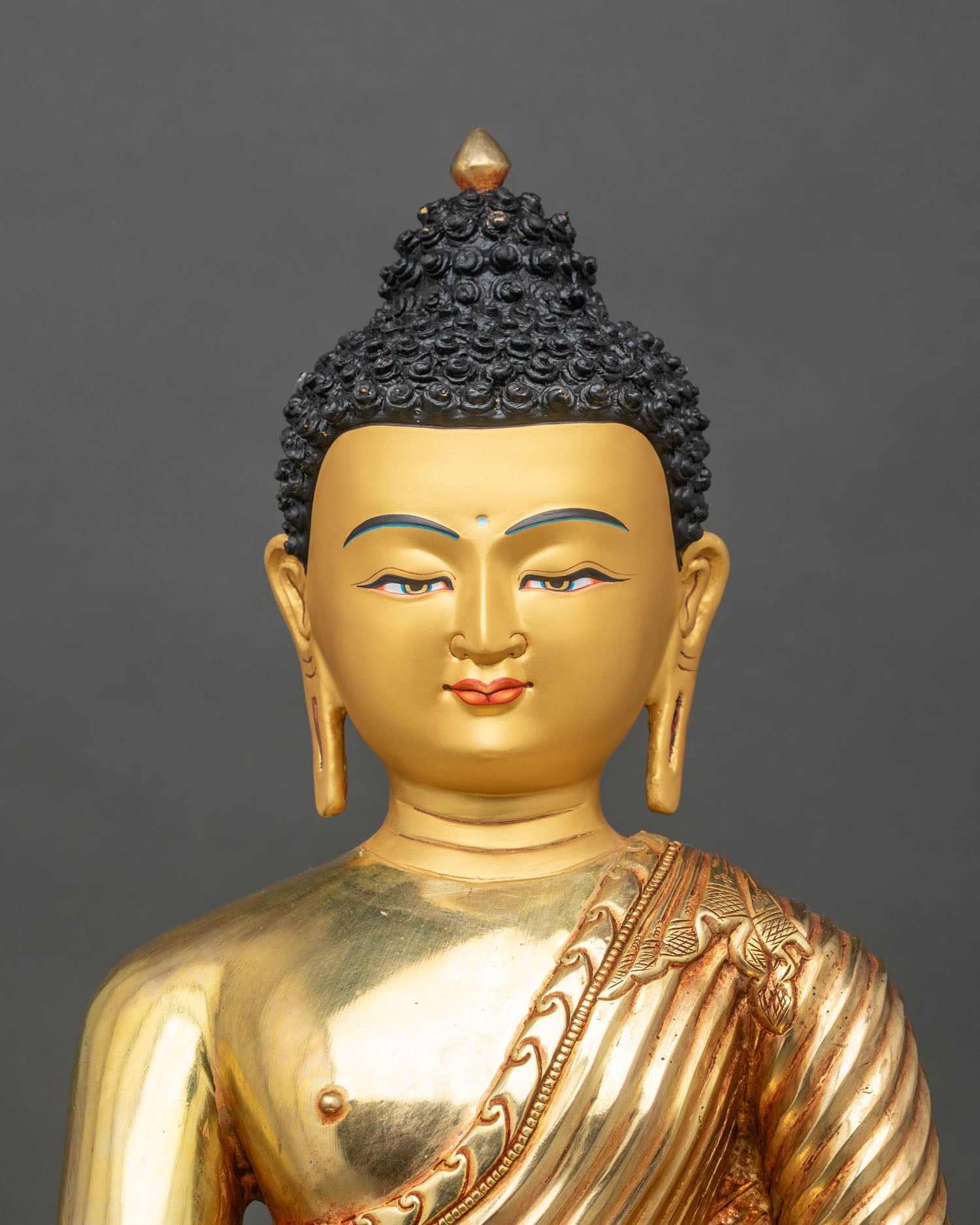 Regular close-up of Shakyamuni Buddha statue showing detailed robes and gold finish