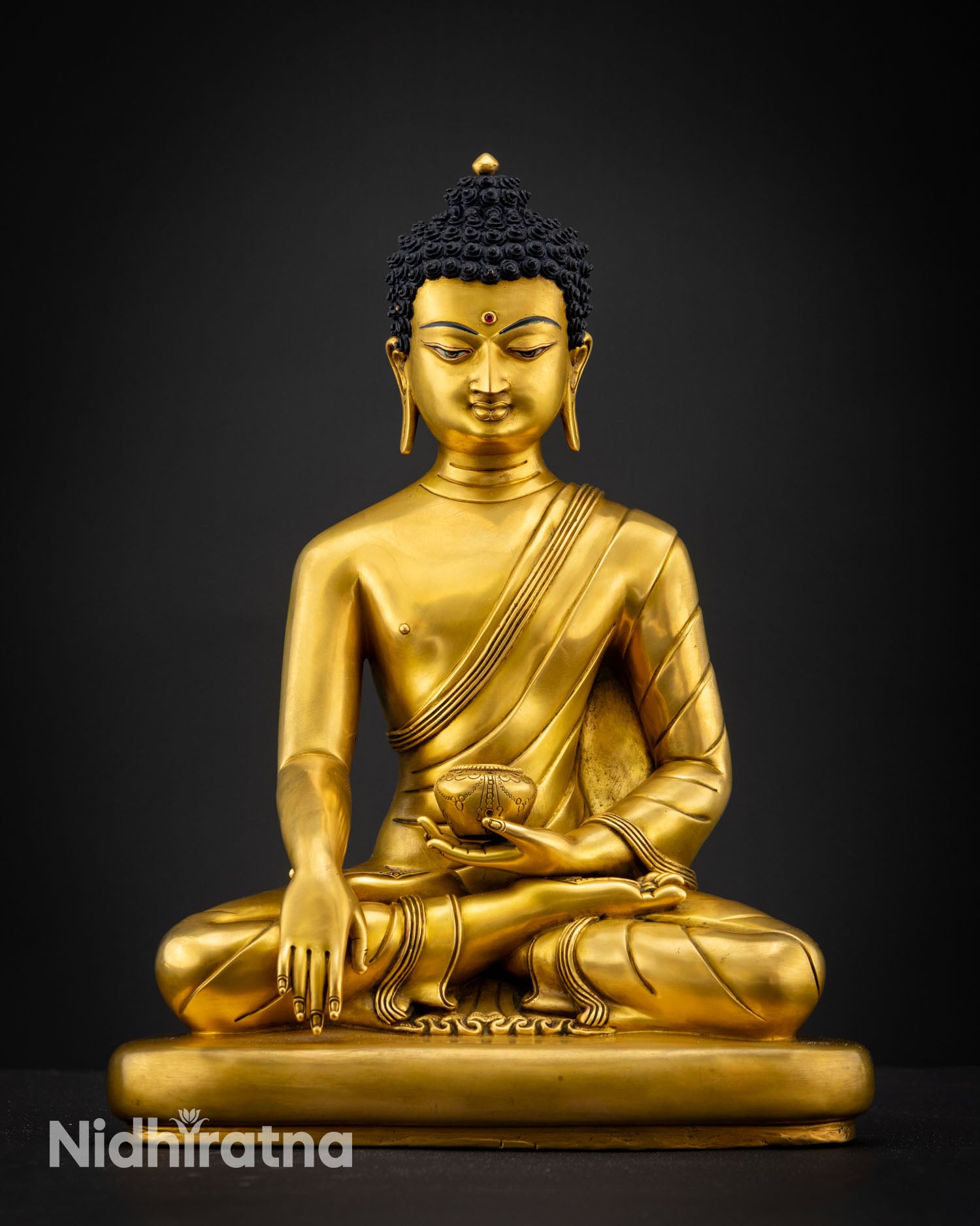 Regular close up view of Shakyamuni Buddha sculpture showing calm facial expression gold gilded details and intricate robes with Himalayan craftsmanship