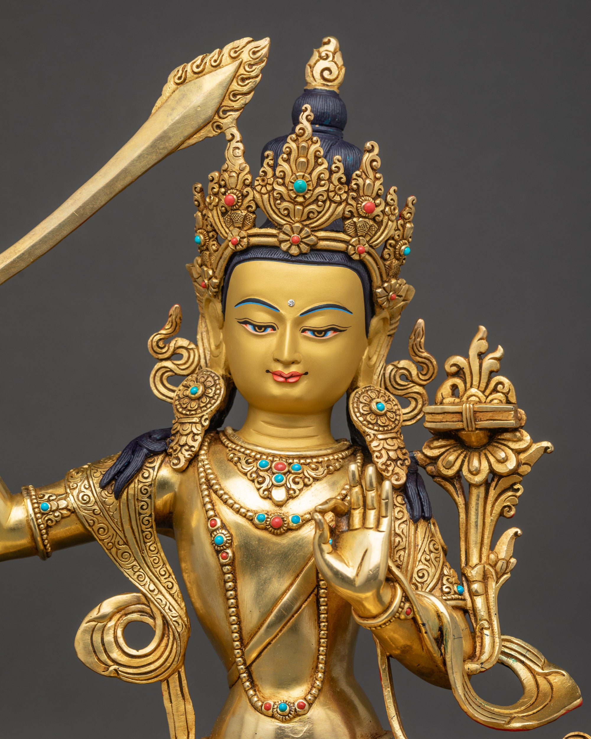 regular close up Manjushri Buddha statue showing intricate robes and gold-gilded details
