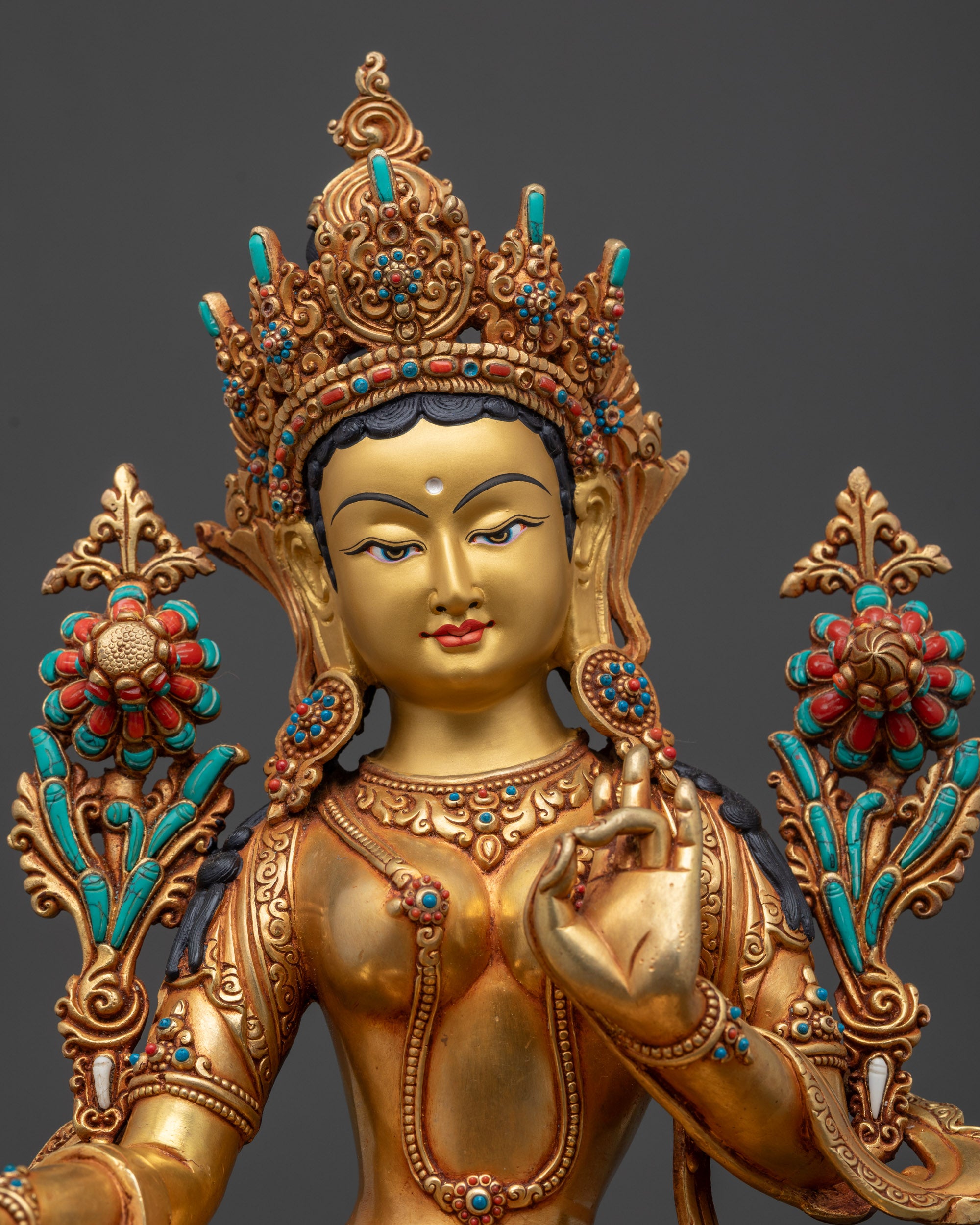 regular close up green tara buddhist idol showing utpala flower and jeweled crown
