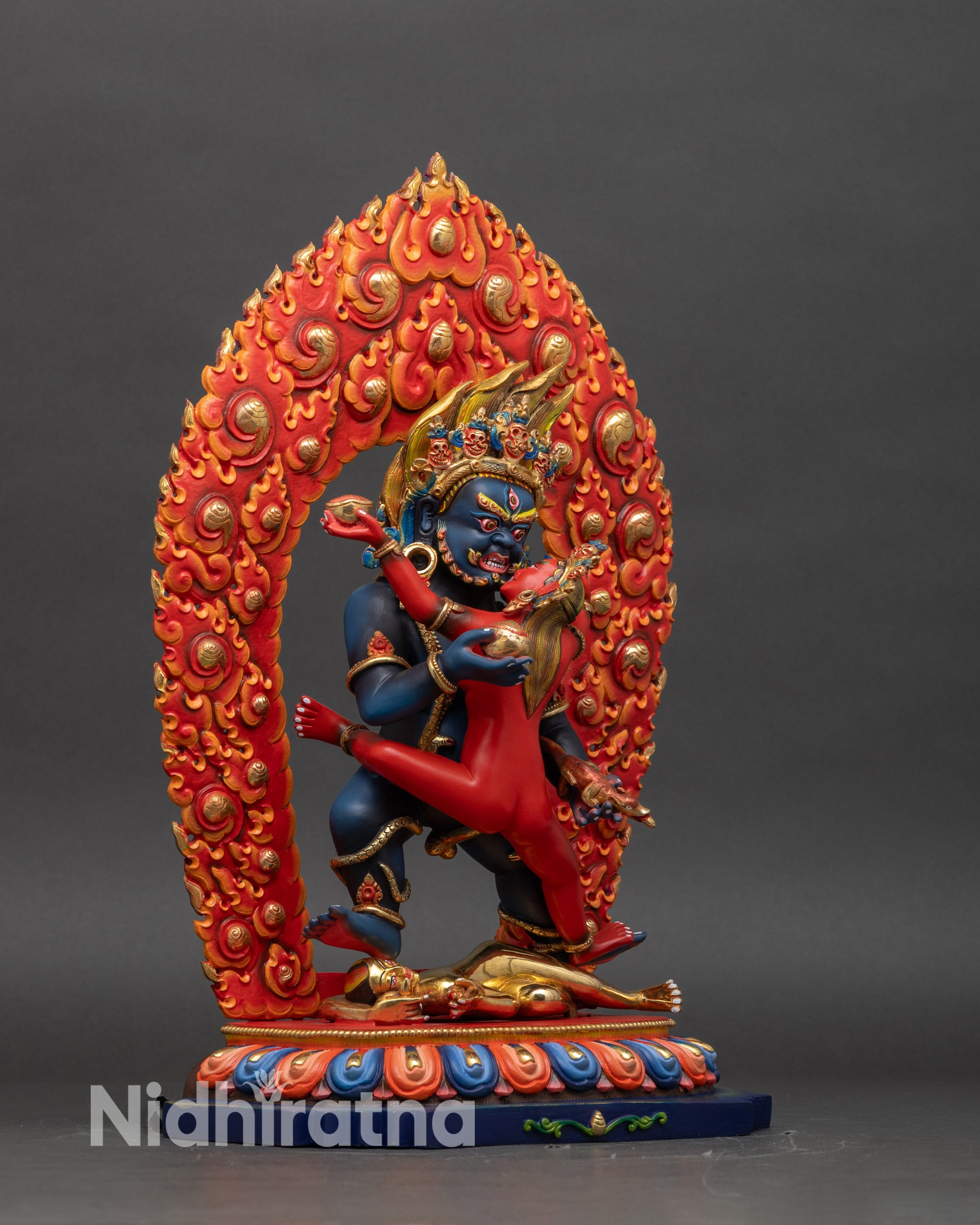 Right profile of Black Dzambhala Yab Yum statue subduing human figure on lotus base