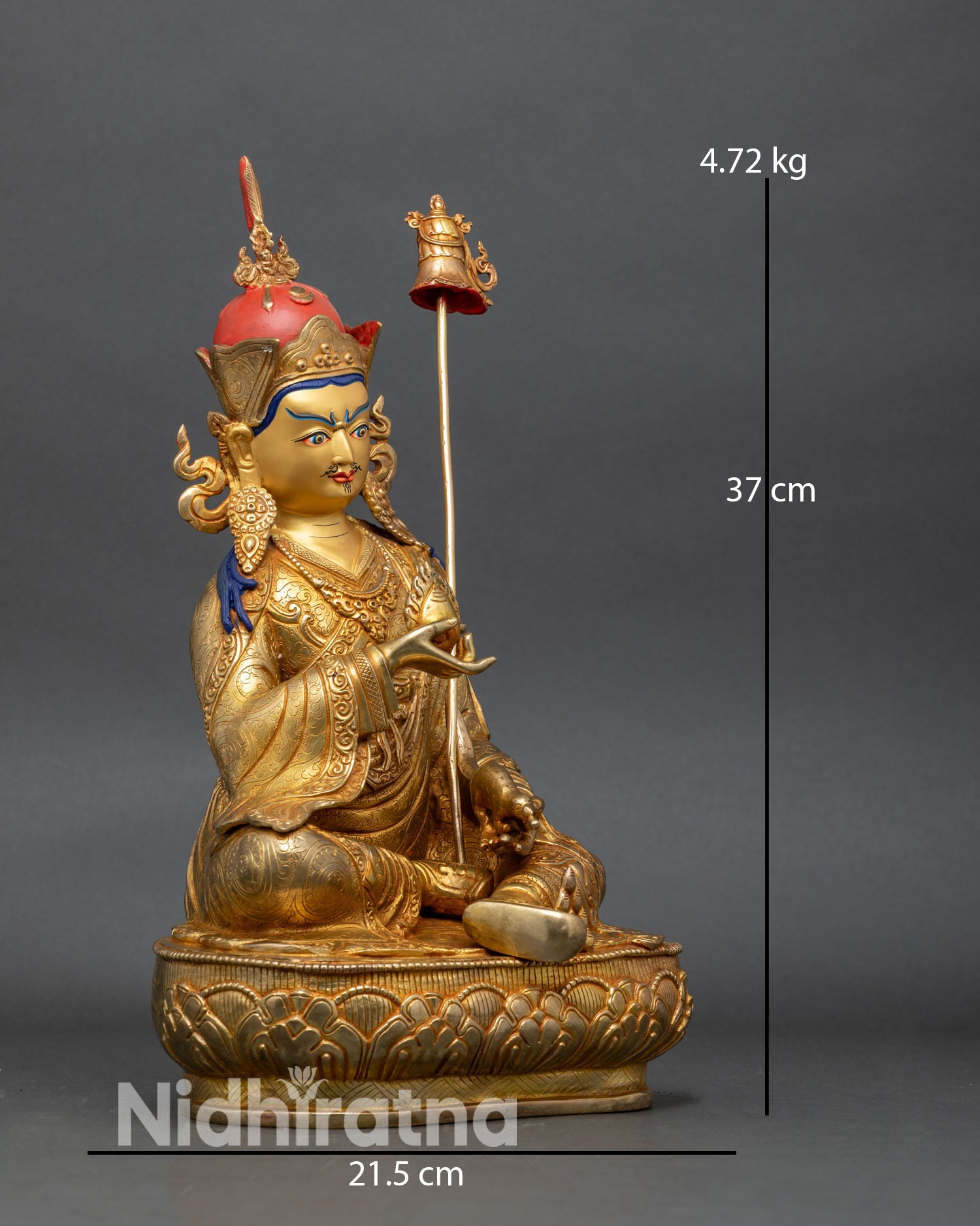 right side view of guru norlha statue seated on lotus with jeweled khatvanga staff