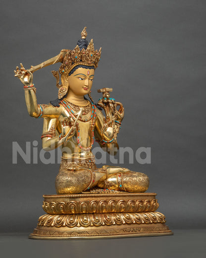 Right side view of seated Maha Manjushri statue with flaming sword, bow and arrow on double lotus base