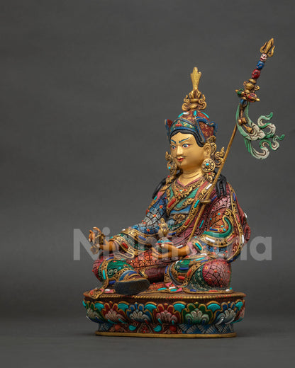 Guru rinpoche statue showing gold fire gilded details semi precious stones and royal garments.