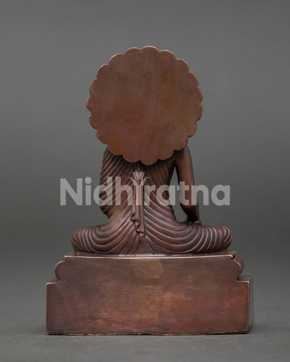 Shakyamuni Buddha sculpture with ornate pedestal halo design and oxidized copper finish representing enlightenment and wisdom.