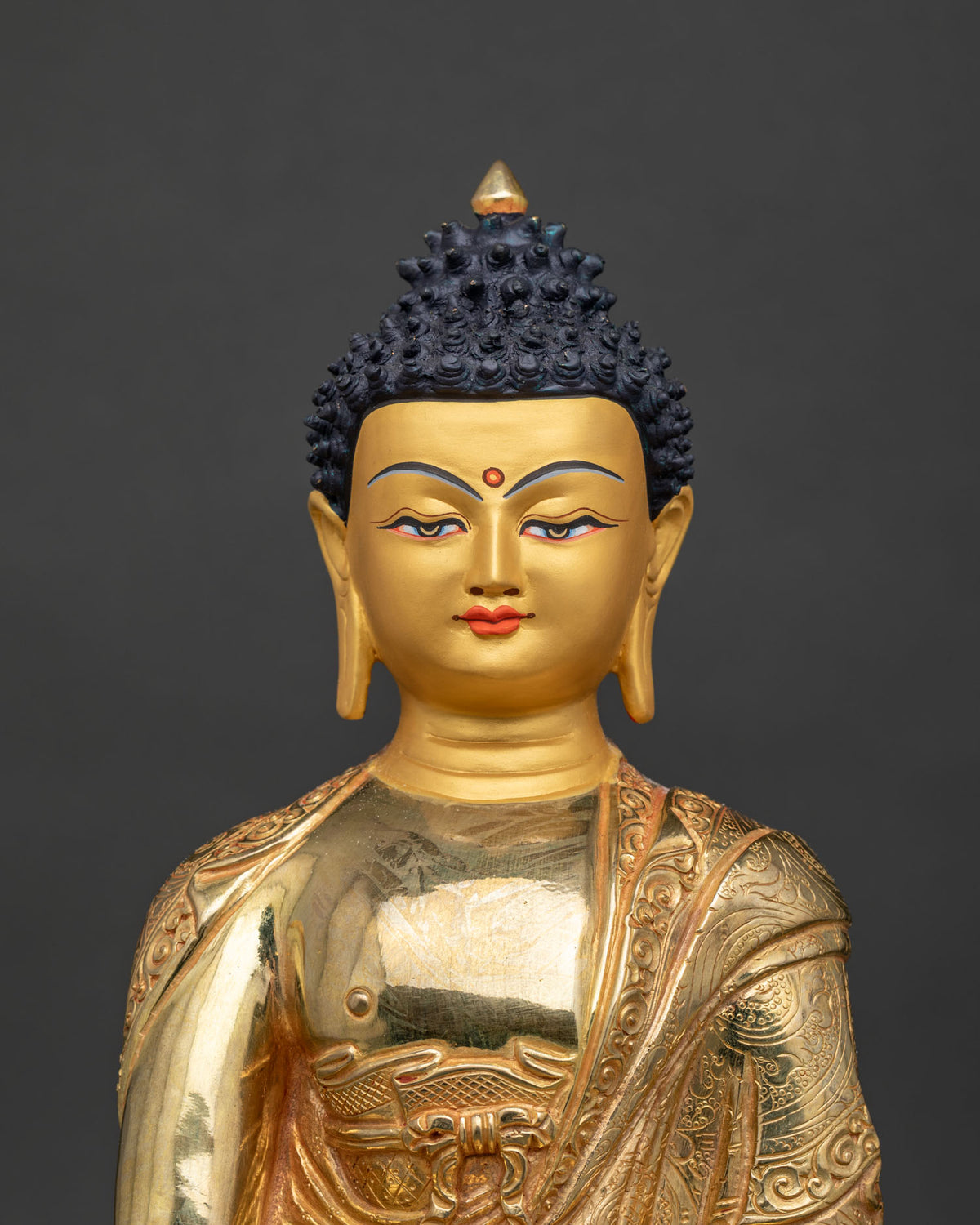 Shakyamuni Buddha statue 24k gold painted face close up.