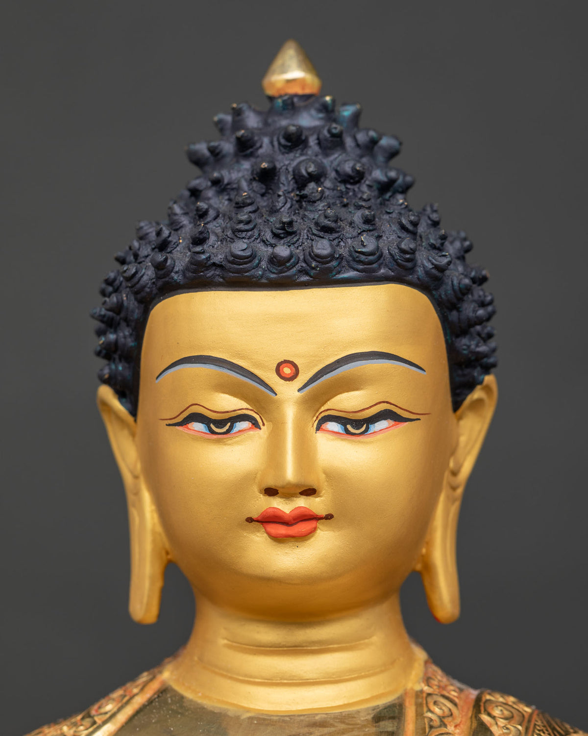 Shakyamuni Buddha statue 24k gold painted face detailed close up.