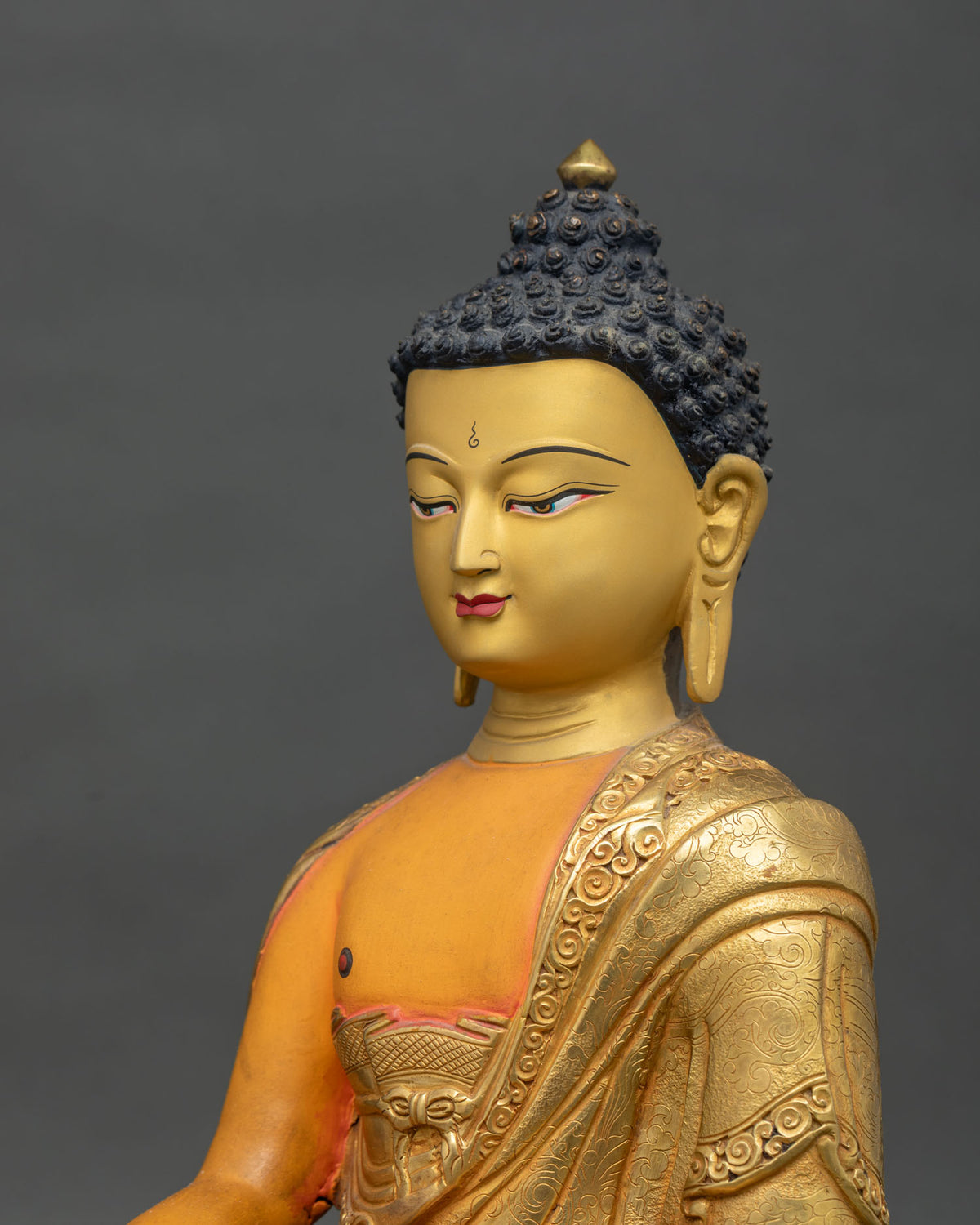 Shakyamuni Buddha statue wearing a monk robe decorated with floral motifs and finished with acrylic painting and gold gilding.