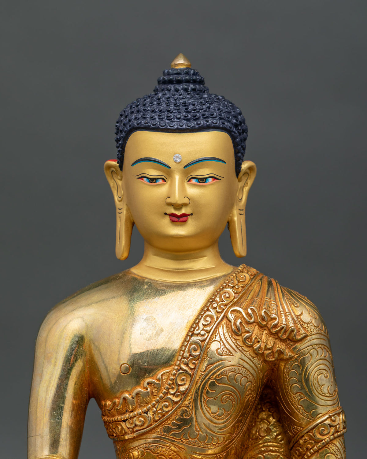 Shakyamuni Buddha Statue close up 24k gold painted face Buddhist sculpture.