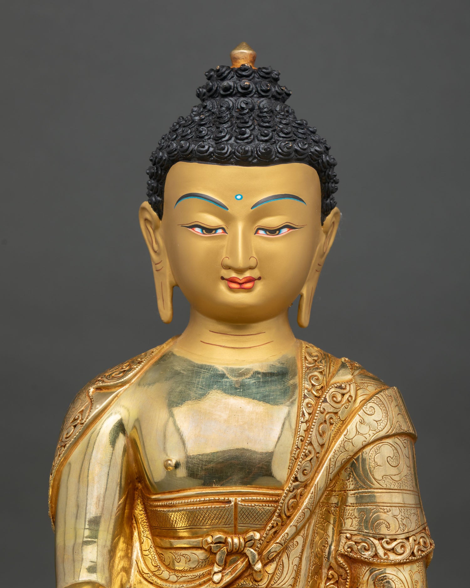 shakyamuni buddha statue close up showing intricate robes and fire gilded details