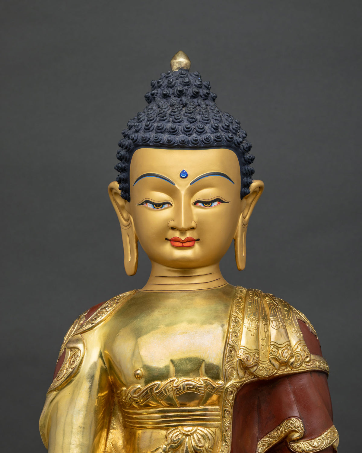 Shakyamuni Buddha statue close-up view, gold gilded robe and hand mudra details