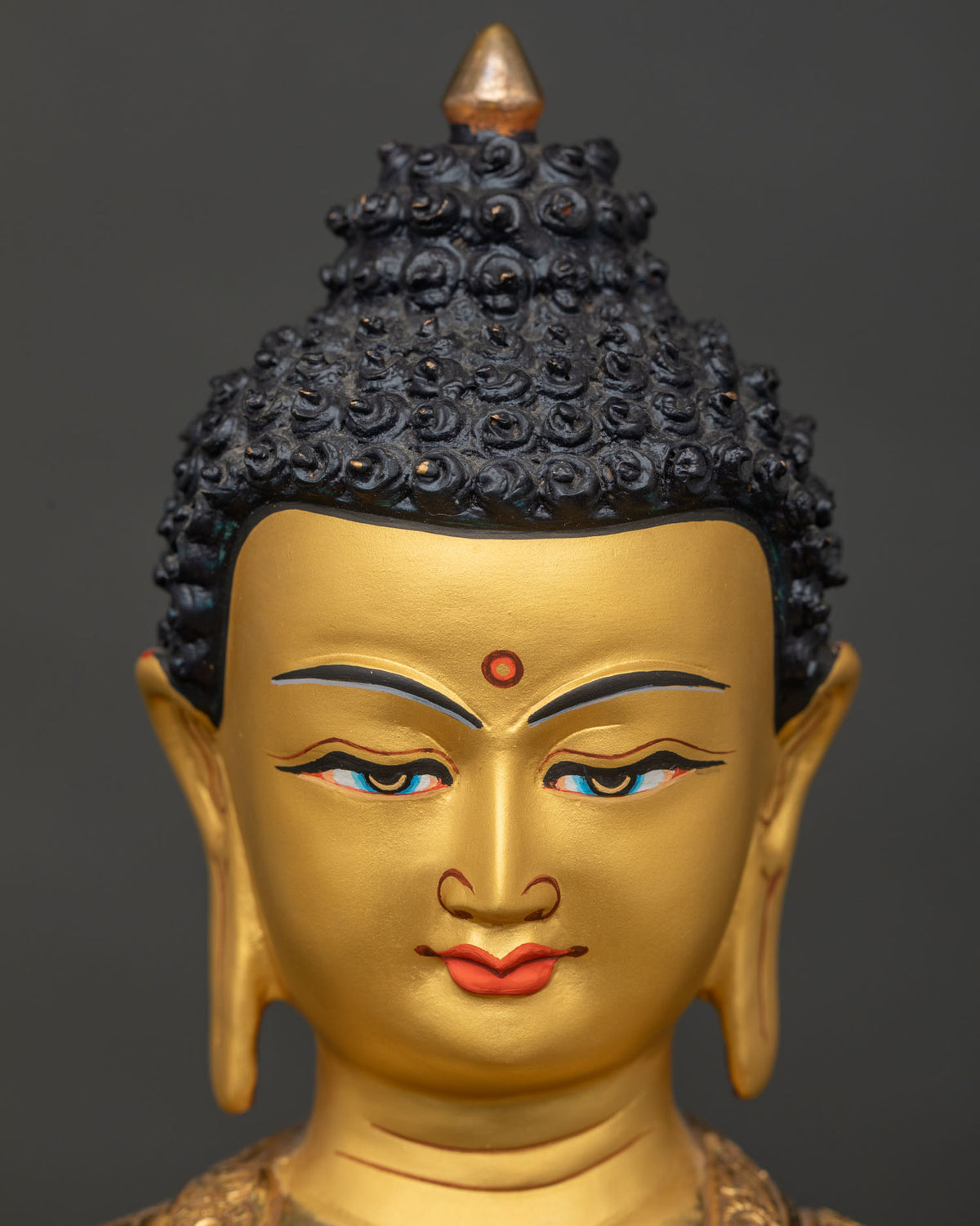 Shakyamuni Buddha statue face close up serene expression 24k gold painted face.