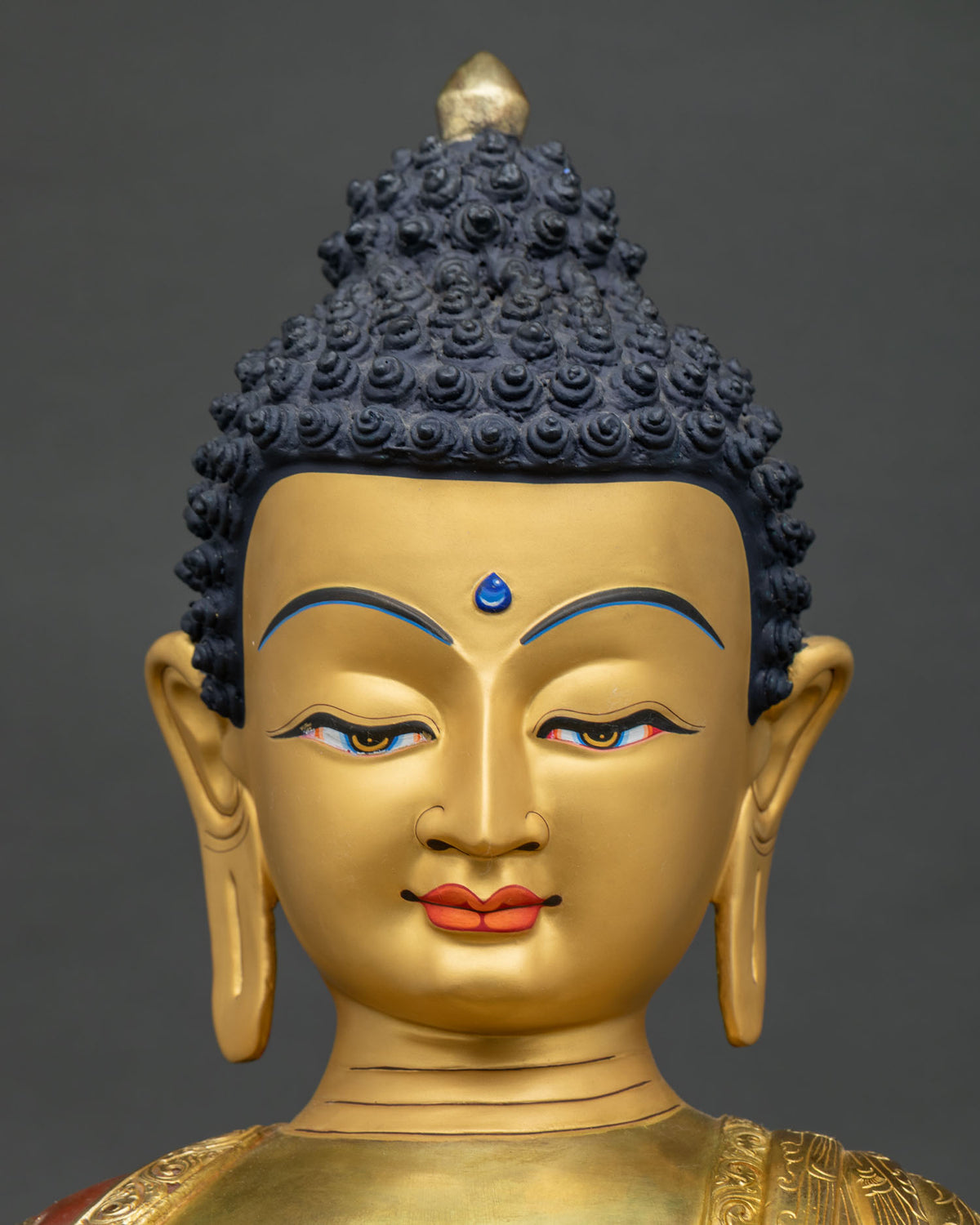 Shakyamuni Buddha statue face close-up, serene gold-painted meditative expression