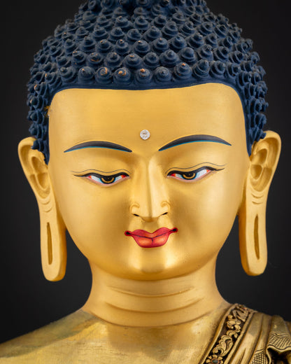 Shakyamuni Buddha statue face close-up showing Urna jewel, blue Ushnisha hair and half-closed eyes