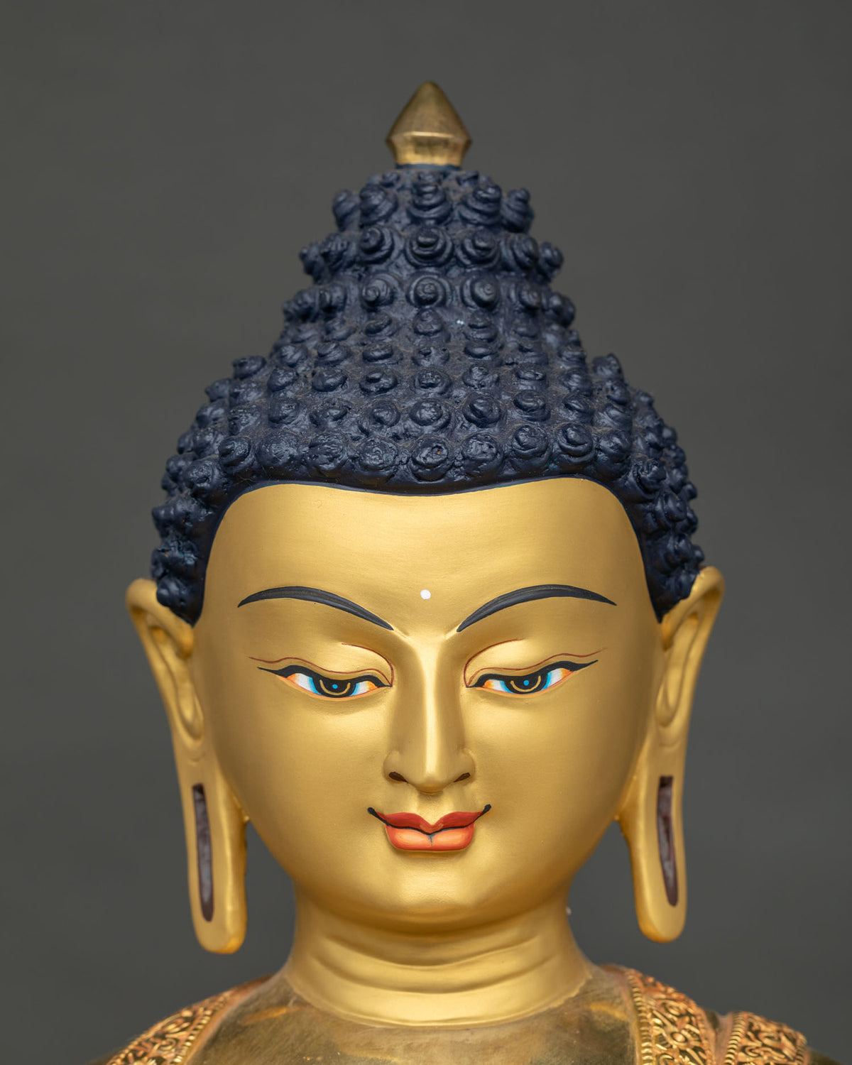 Shakyamuni Buddha statue face close-up with serene hand-painted expression and blue curled hair