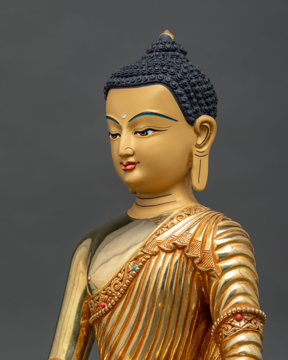 Shakyamuni Buddha statue face detail serene expression gold gilded finish.