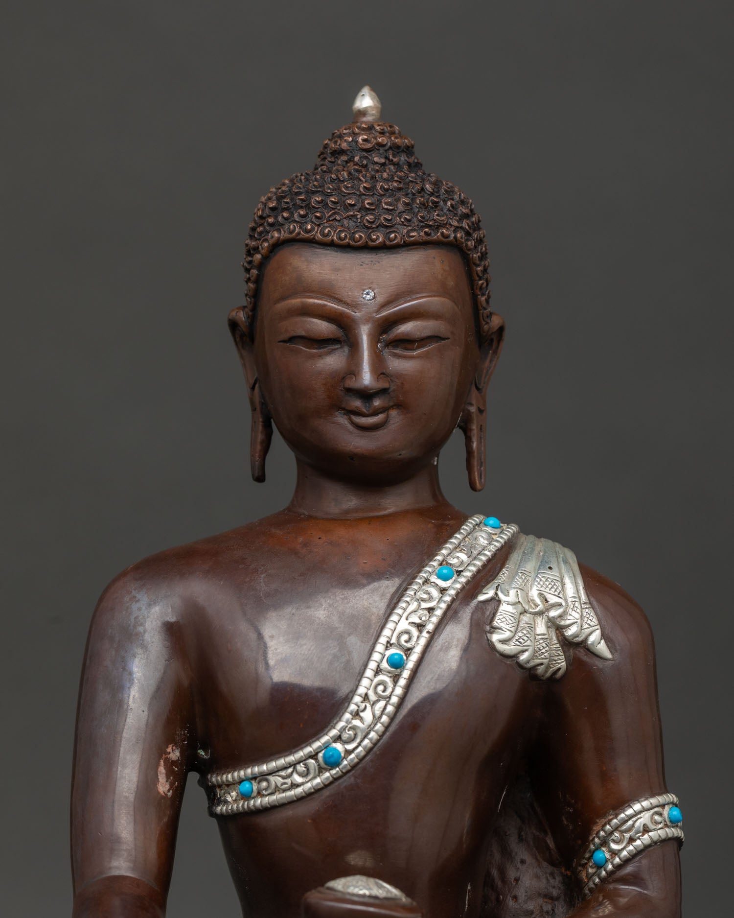 Shakyamuni buddha statue front closeup showing serene face and intricate nepali craftsmanship.