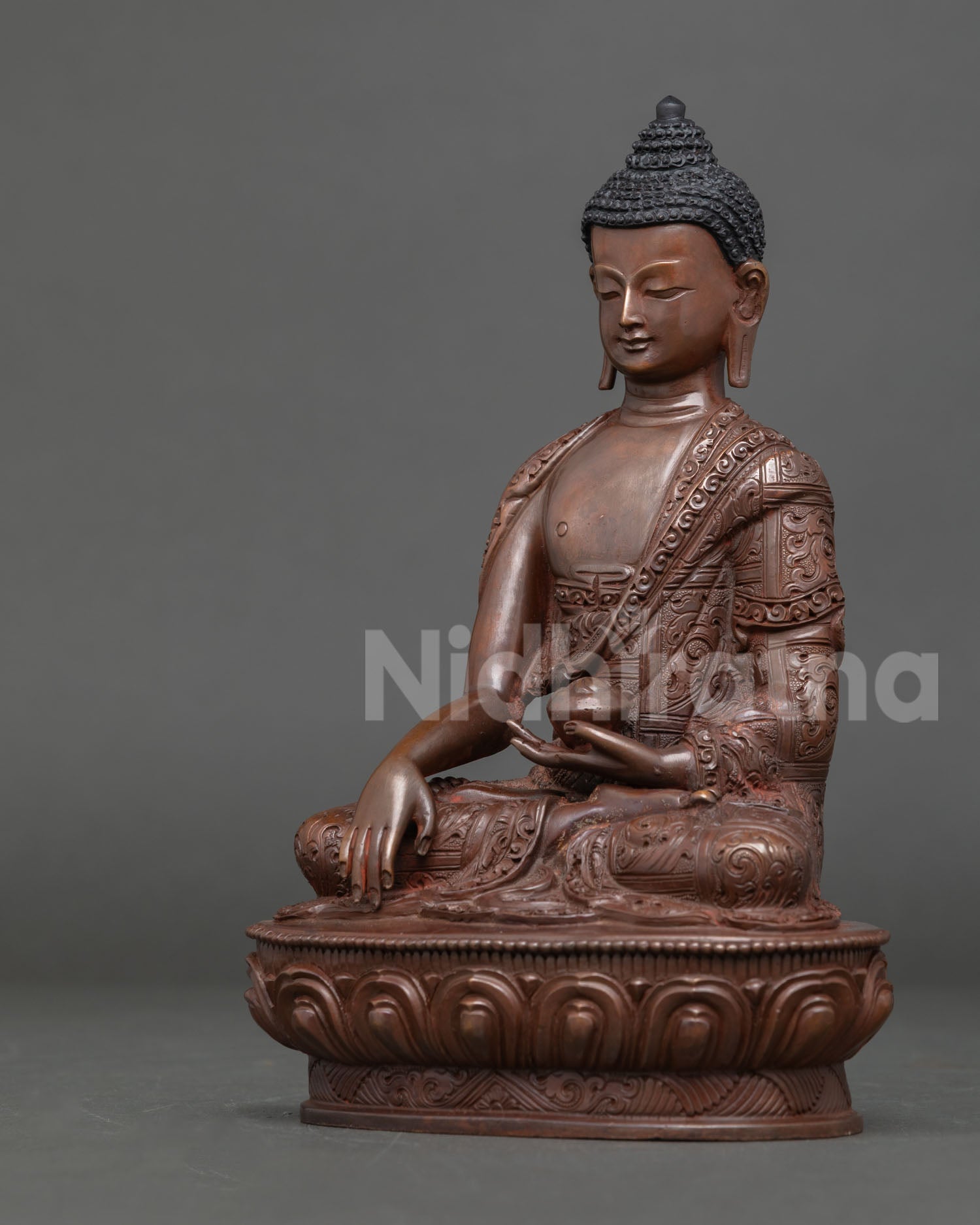 Shakyamuni Buddha statue handcrafted in Nepal using copper and lost wax technique with oxidized finish, seated on a lotus throne in earth touching mudra.