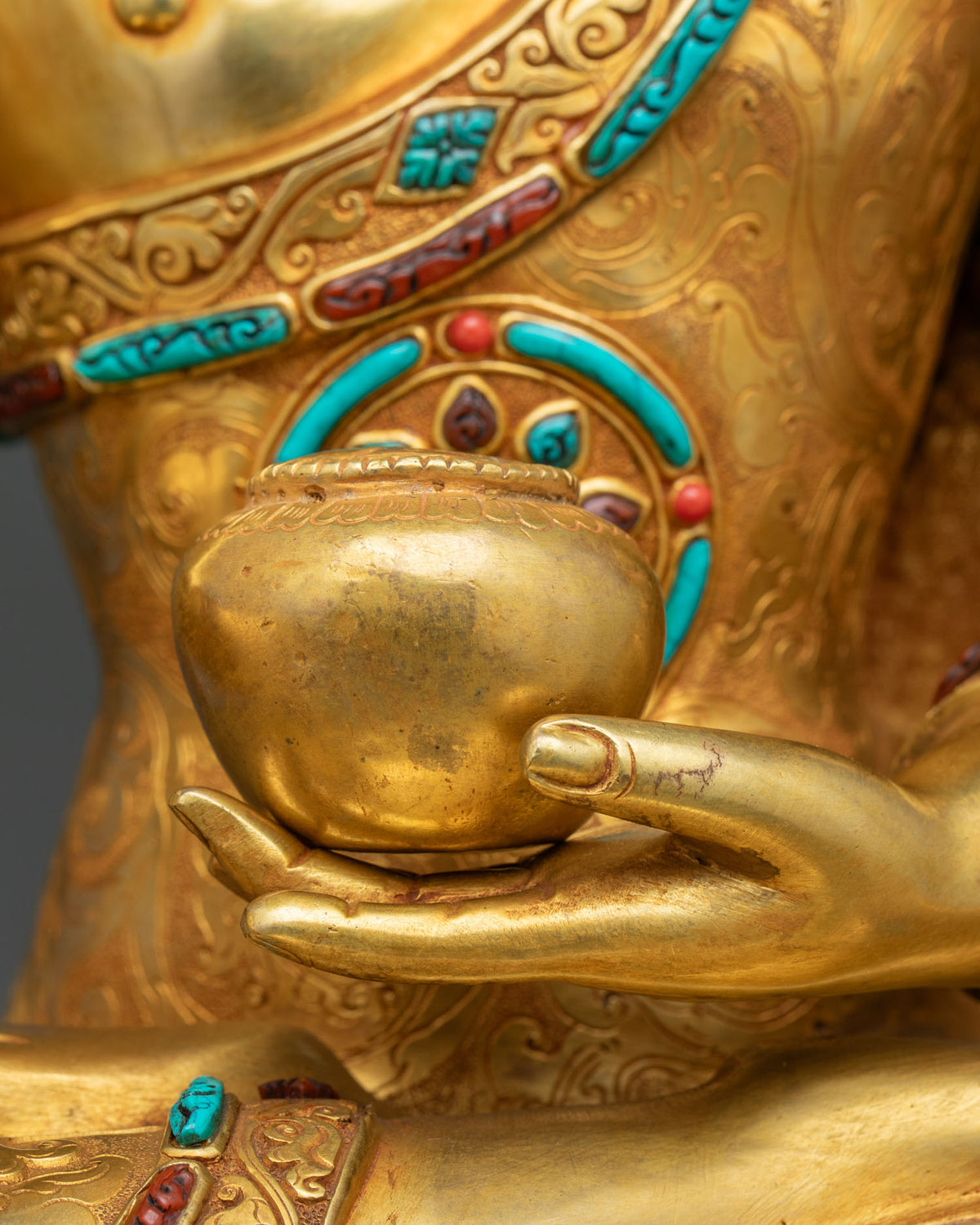 Shakyamuni Buddha statue left hand holding a gold patra bowl, close-up detail
