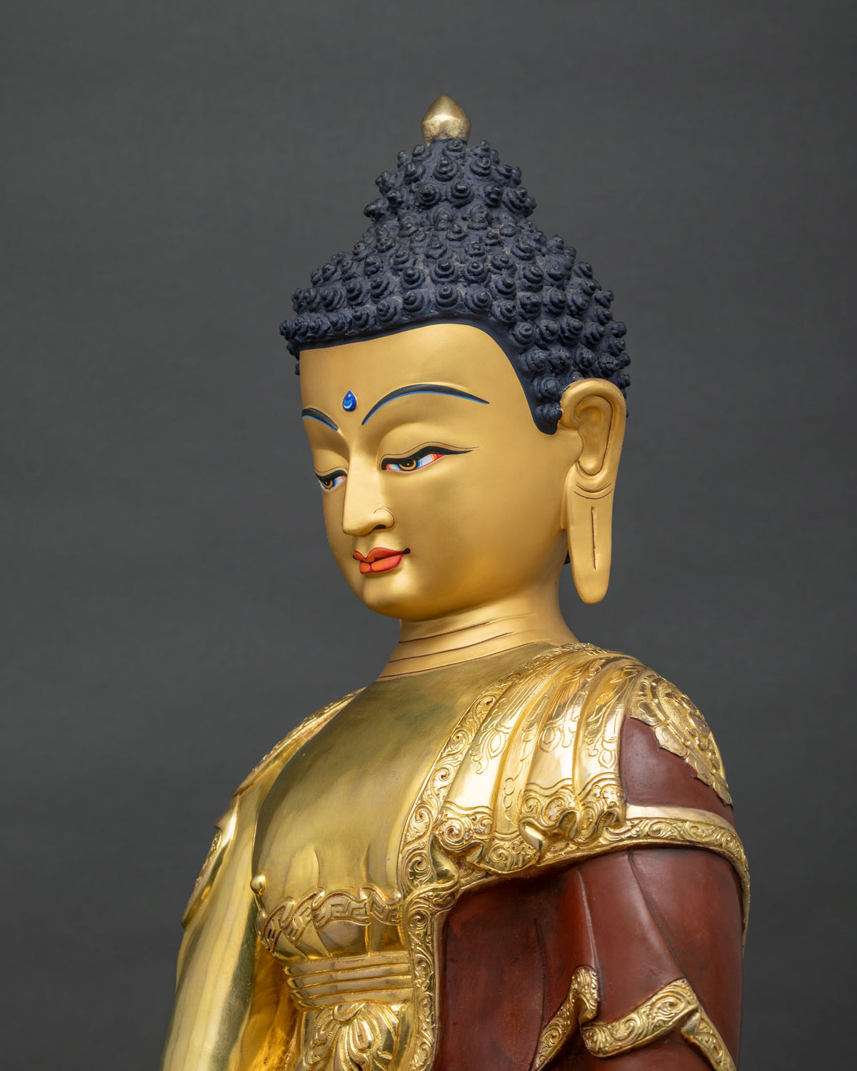 Shakyamuni Buddha statue side close-up, detailed gilded robe and mudra carving