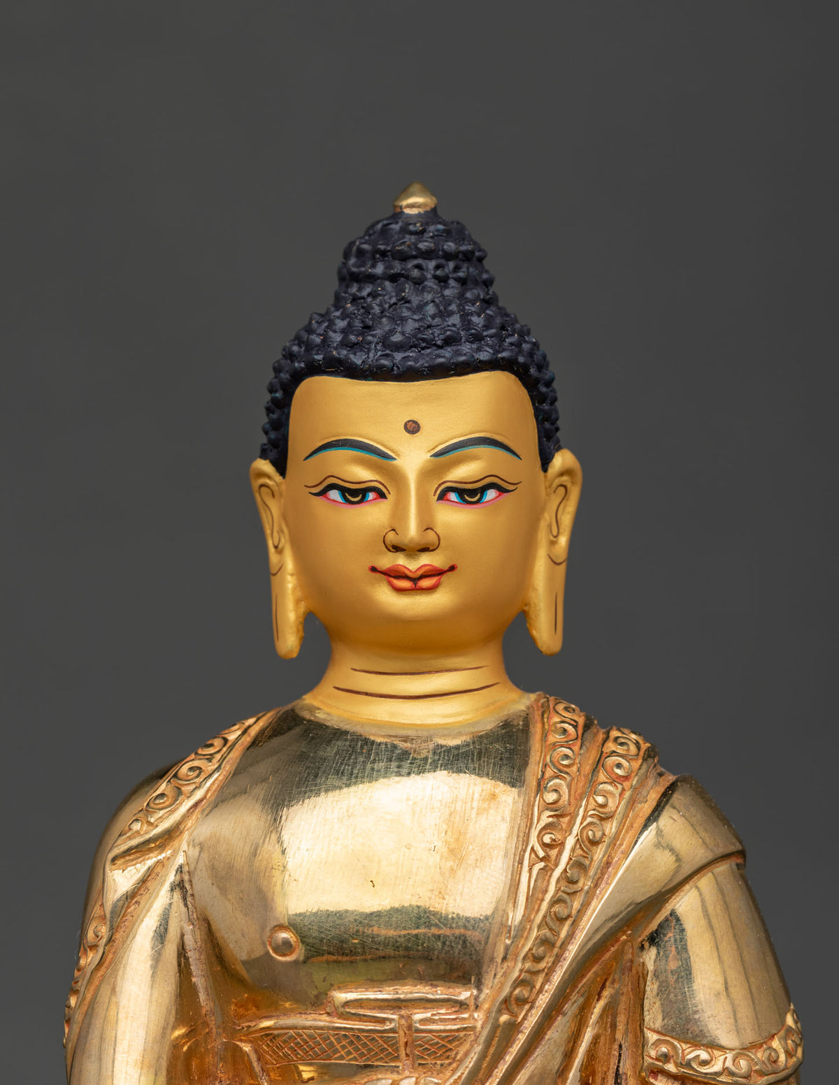 Shakyamuni buddha statue with 24k gold painted face seated on intricately carved lotus seat.