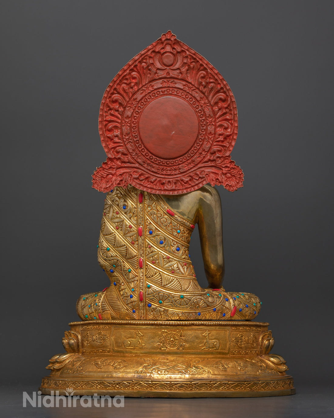 back profile of gold gilded shakyamuni buddha statue where the halo is painted red with poster color